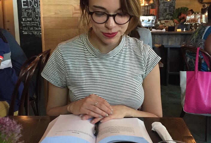 Photo of Becca Rothfeld perched over a book